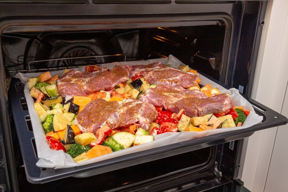 Seasoned vegetables with pork on a baking sheet.